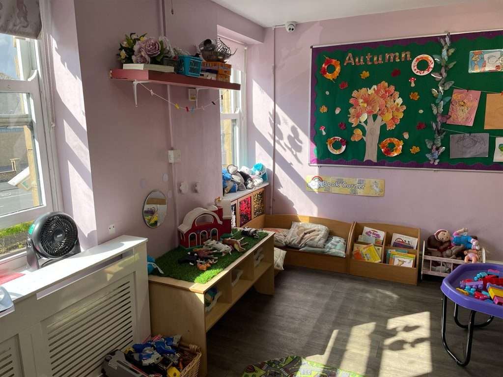Autumn-themed display board and farm role-play table in a nursery playroom at Ducklings Childcare, Moldgreen