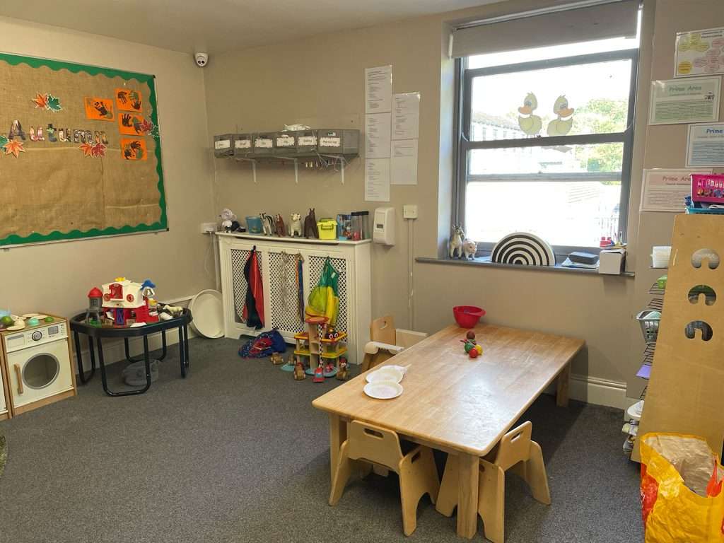 Children's artwork display and wooden dining table in a nursery room at Ducklings Nursery, Moldgreen