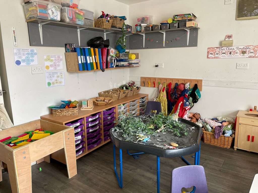 Cloakroom storage, coat pegs and a messy play table in a nursery room at Ducklings Childcare, Huddersfield