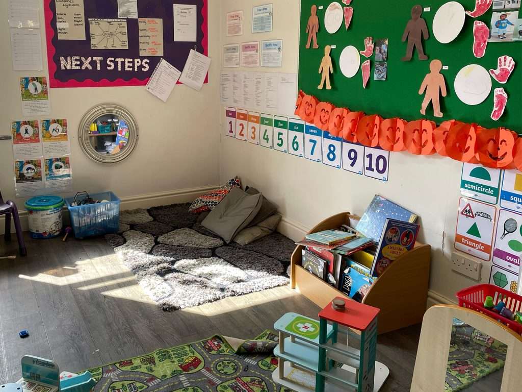 Cosy reading corner with cushions and a learning journey display in a nursery classroom at Ducklings Nursery, Moldgreen