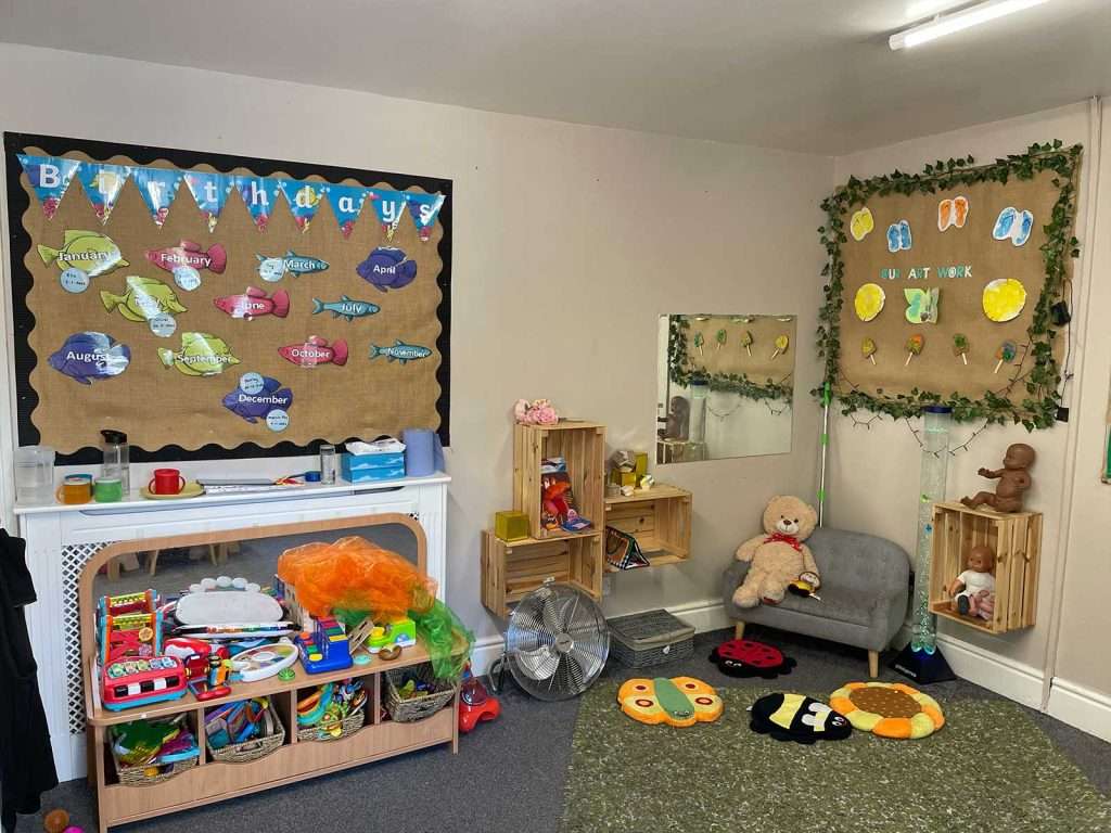 Dressing-up corner and birthday display with soft seating in a nursery playroom at Ducklings Childcare, Huddersfield