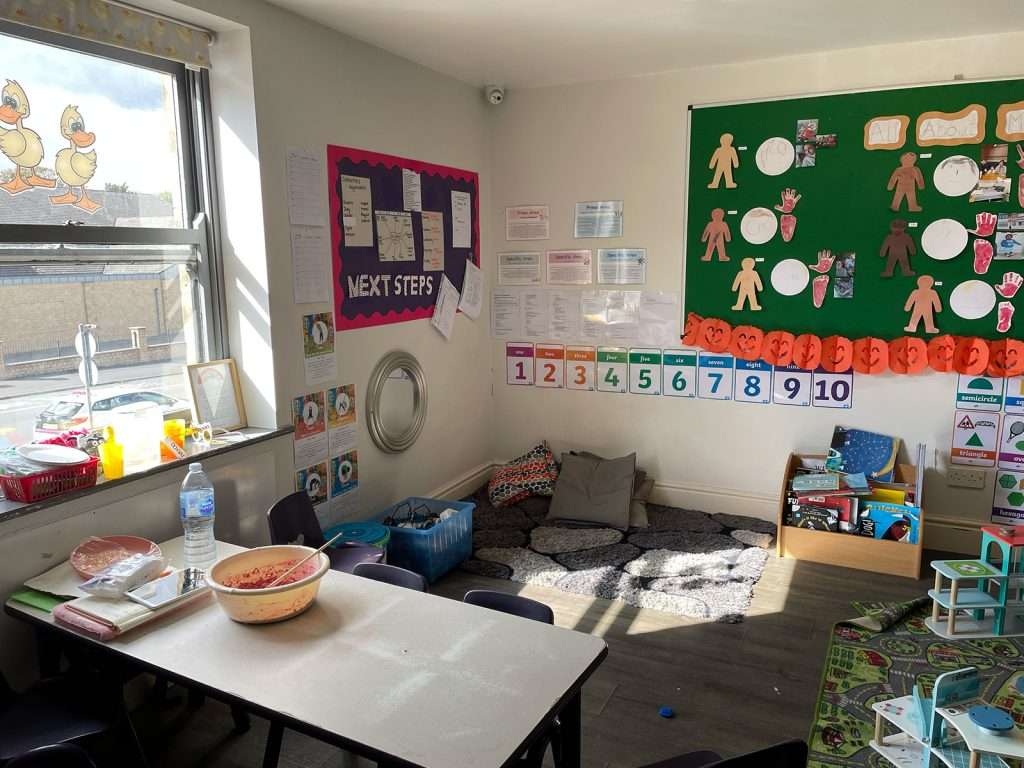 Reading corner, snack table and numbers display in a nursery classroom at Ducklings Nursery, Moldgreen